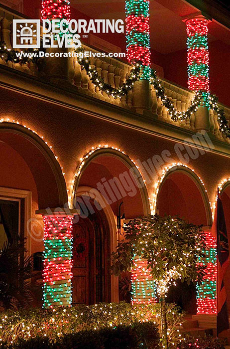Red-and-Green-stripped-columns-with-balcony-column-swags-and-arched-outlined-with-clear-minis.-www.decoratingelves.com