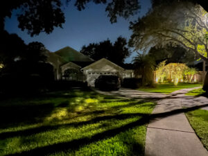 2 homes on a street, one well lit with landscape lighting and the other is dark